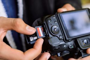 Inserting high capacity memory card into photo camera outdoors